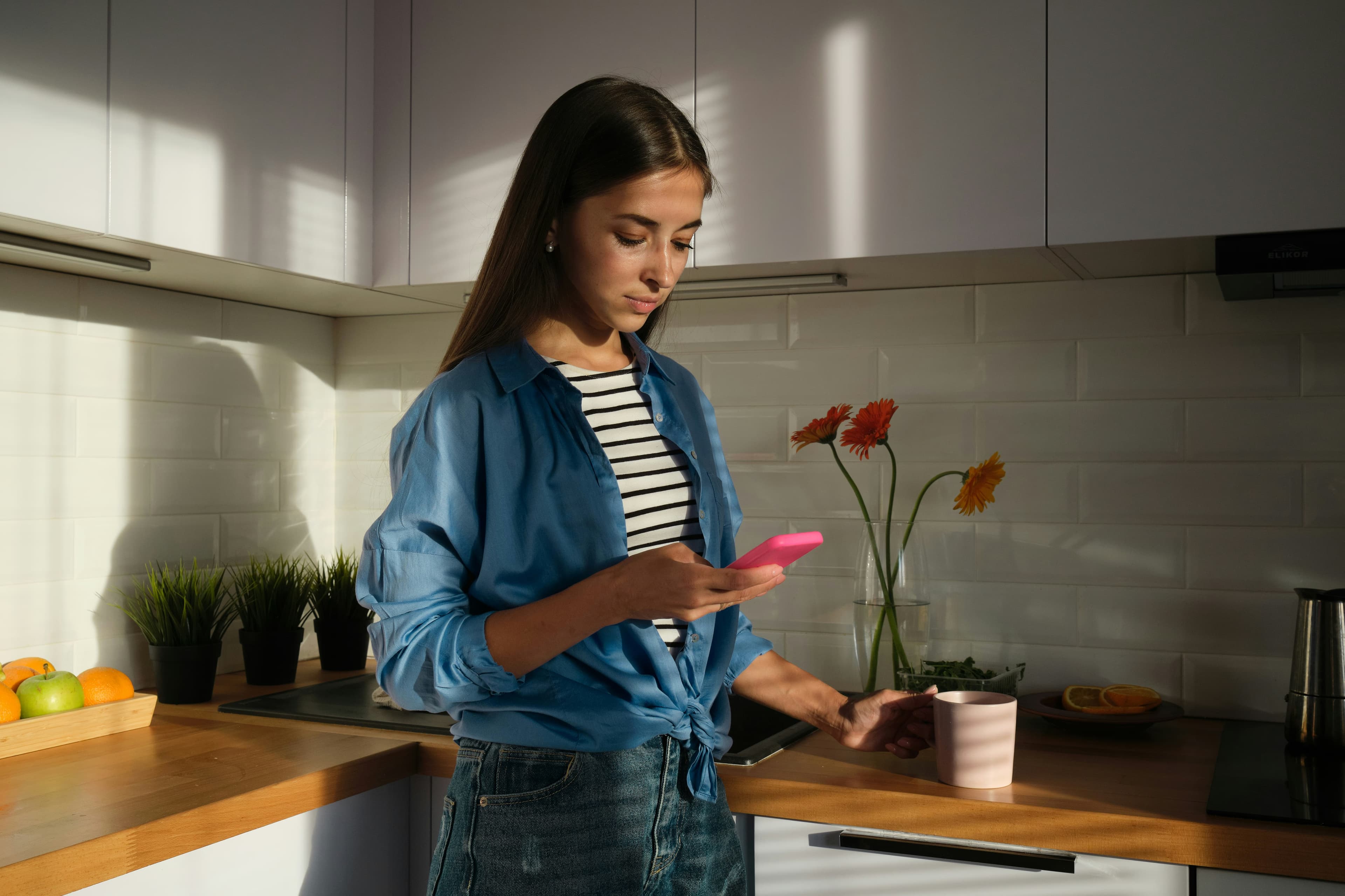 Kvinna kollar sin telefon i köket